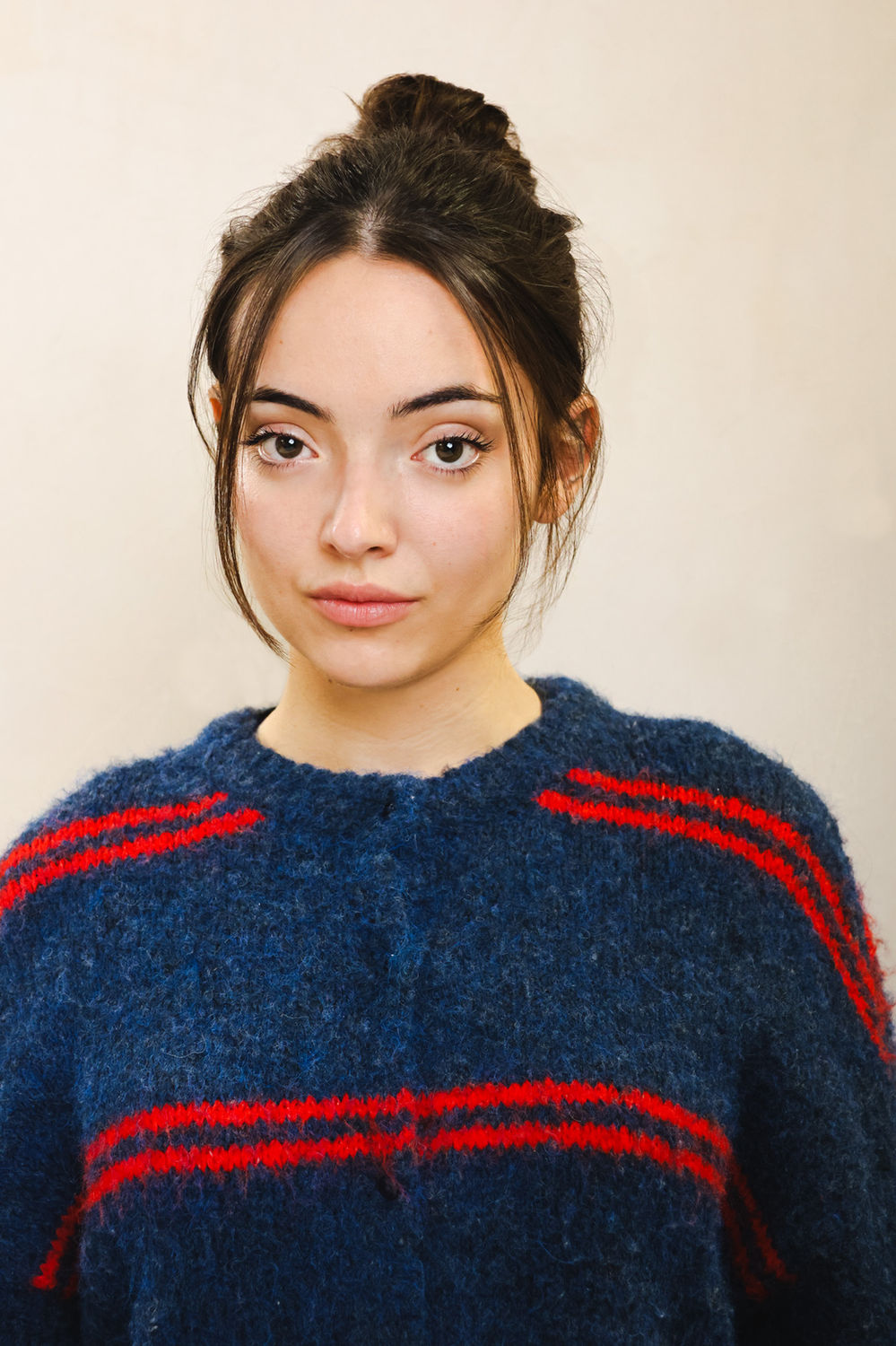 Natural actor headshot of a person in a blue knit jumper against a neutral backdrop, suited to Spotlight-ready casting profiles.